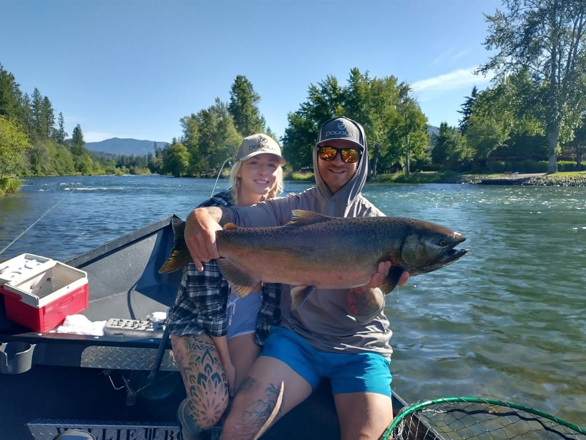 A couple holding a salmon on the drift boat