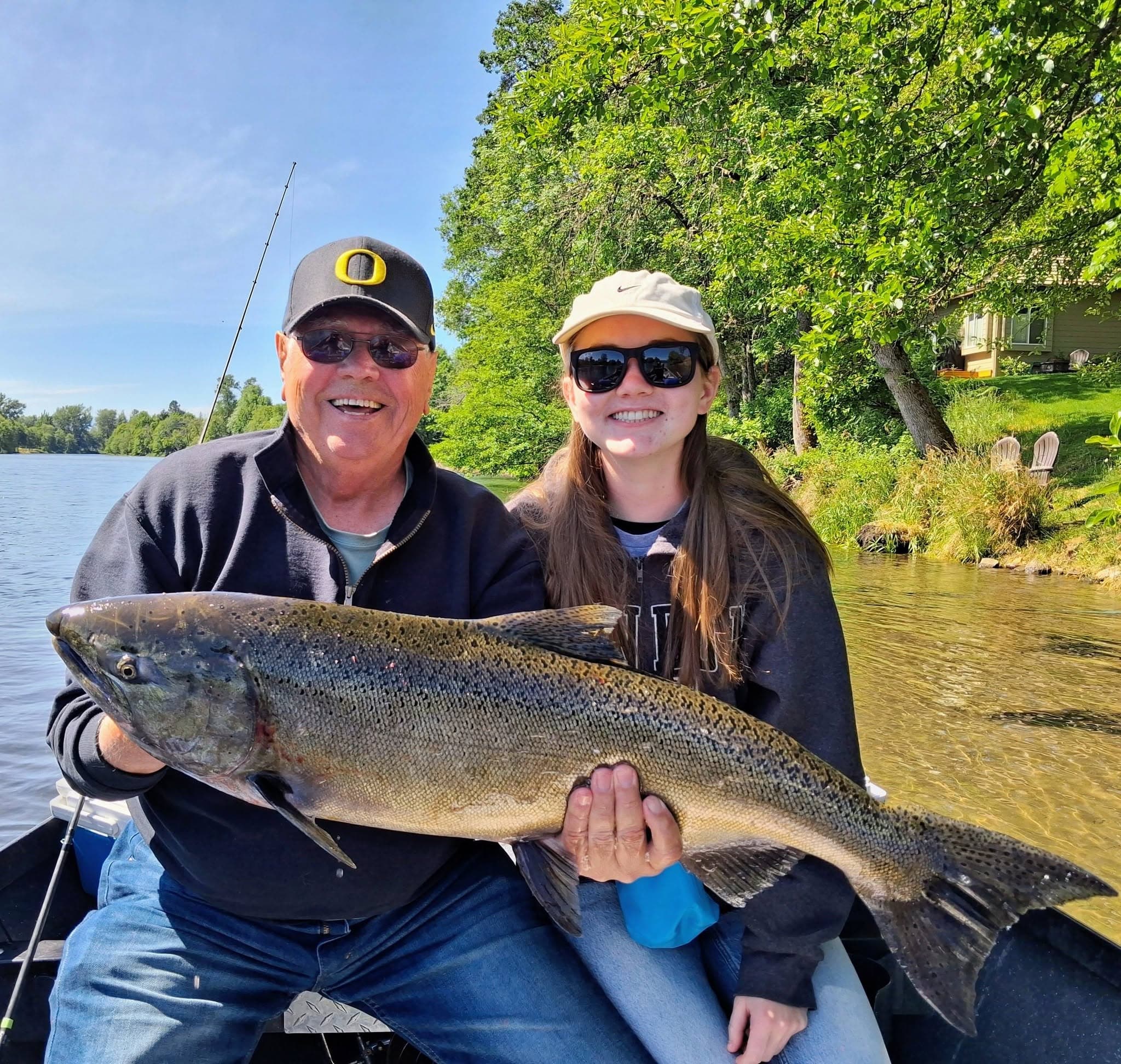 A grandfather and granddaughter holding a large salmon
