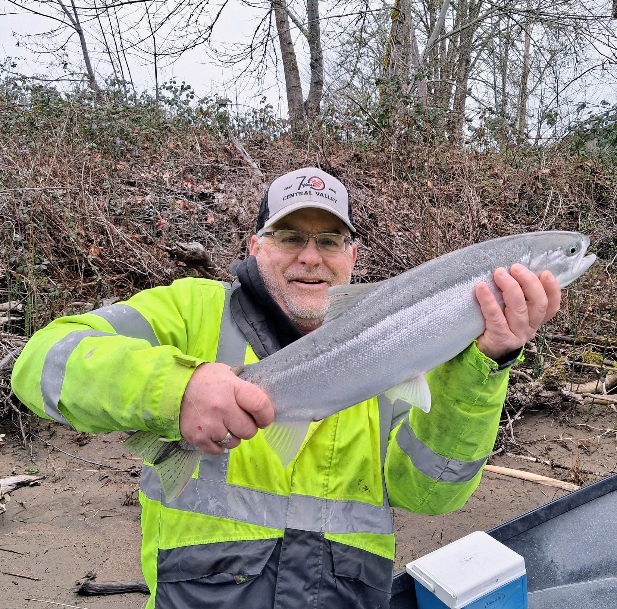 Angler holding a chrome steelhead on the bank